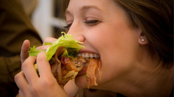 Mujer comiendo un sándwich.