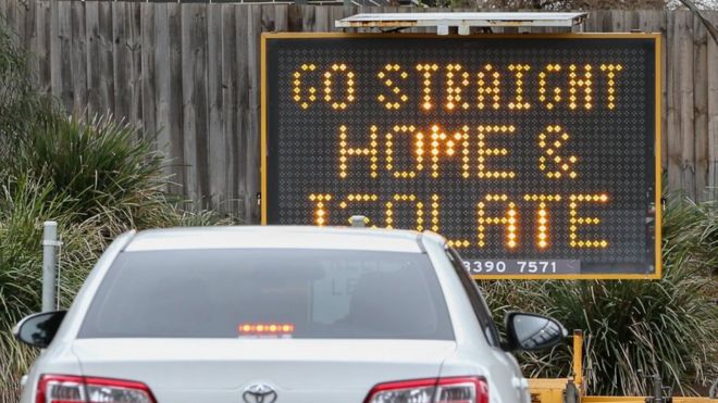 A sign reading 'Go straight home and Isolate' is seen at the exit of a drive through Covid-19 testing site in Melbourne