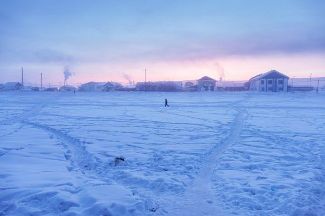 Мужчина гуляет по деревне на рассвете. Климатический фактор здесь вездесущий: в феврале 1892 года самая низкая температура в мире (без учета Антарктиды) была зафиксирована в Верхоянске. И если деревня борется за звание самой холодной деревни в мире с Оймяконом, она, тем не менее, держит рекорд самого большого температурного диапазона на Земле: 105 ° C (189 ° F) с -67,8 ° C зимой и 37,3 ° C летом.