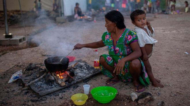 Venezuelana prepara comida para o filho na rua