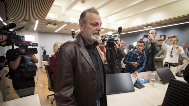 Eirik Jensen arrives at court, surrounded by news media pointing cameras, on 18 September