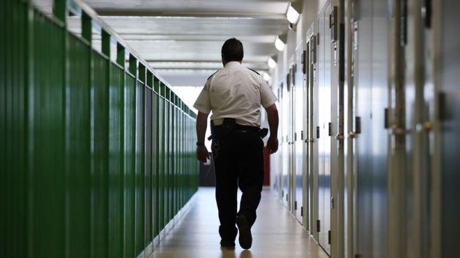 Офицер тюрьмы проходит мимо дверей камеры в HMP Berwyn, Wrexham