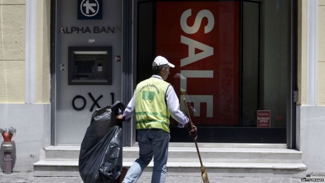 Уличный уборщик возле магазина и банкомата в Афинах, 13 июля 2015 года