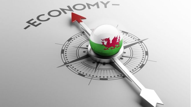Компас с валлийским флагом посередине и стрелкой, указывающей на слово «экономика»