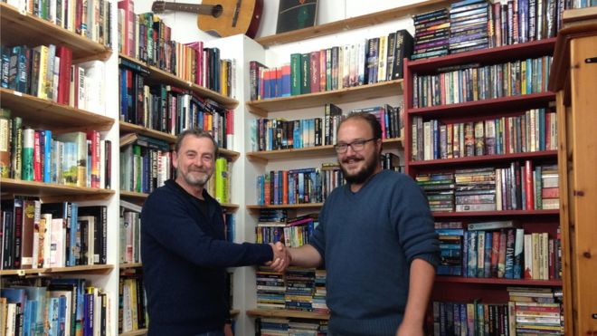 Пол Моррис (слева) и Цейсян Ван Хеерден пожимают друг другу руки в книжном магазине