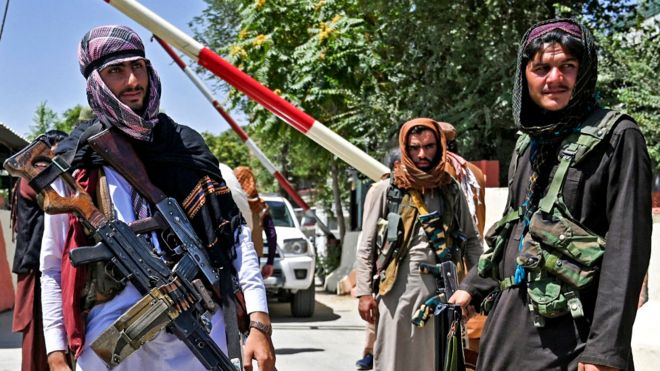 Taliban fighters with weapons stand guard along a roadside near the Zanbaq Square in Kabul on 16 August