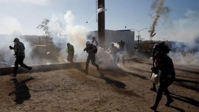 Мигранты и журналисты бегут от слезоточивого газа, выпущенного американским пограничным патрулем возле забора между Мексикой и США в Тихуане, Мексика, 25 ноября 2018 года.