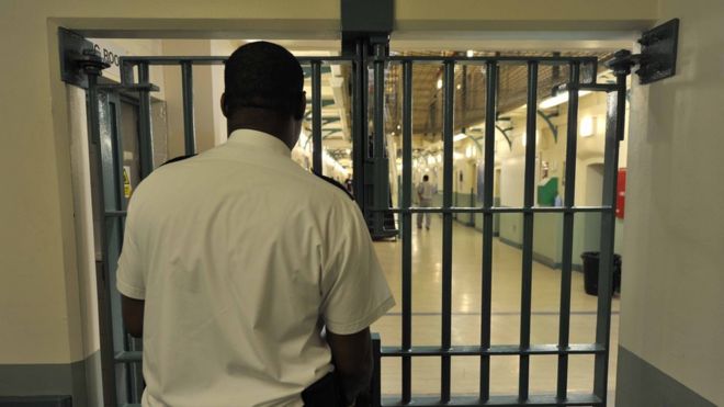Тюремный служащий стоит у закрытых дверей