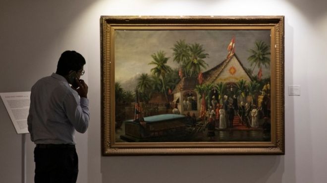 Человек по телефону смотрит на живопись Раджа Рави Варма