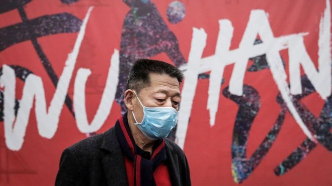 A man wears a mask while walking in the street on 22 January 2020 in Wuhan