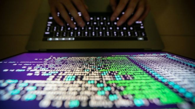 A computer programmer working on fixing Wannacry software in close up shot of screen and hands