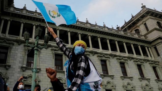 Un mujer con una bandera de Guatemala protesta frente a la sede del Congreso