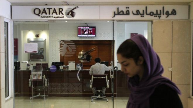 An Iranian woman walks past a Qatar Airways office in Tehran on 6 June 2017