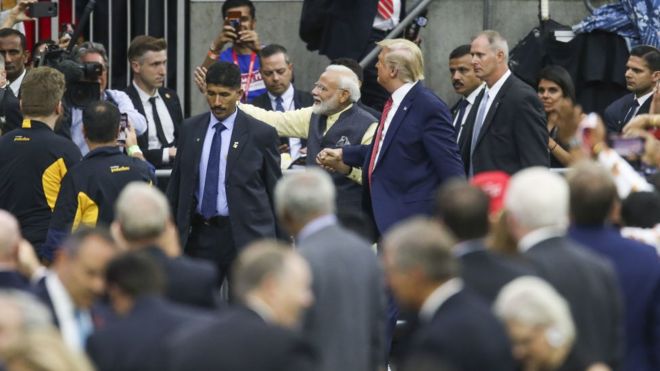 Премьер-министр Индии Нарендра Моди и президент Дональд Трамп идут, держась за руки в Хьюстоне, штат Техас, в окружении толпы