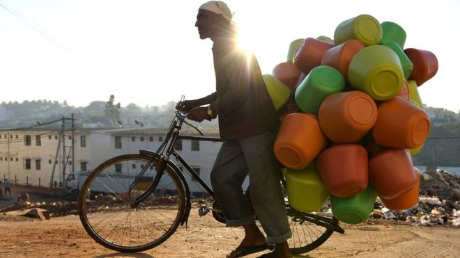 На этом снимке, сделанном 18 марта 2015 года, показан продавец, несущий на своем велосипеде пластиковые пластиковые горшки с водой для продажи домохозяйствам в Бангалоре.