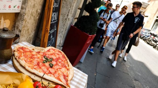 Туристы проходят мимо пиццы в форме сердца в центре Рима 2 августа 2016 года