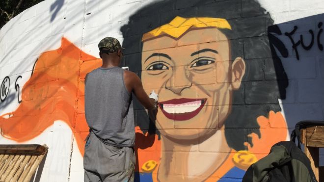 Grafiteiro pinta mural com o rosto sorridente de Marielle