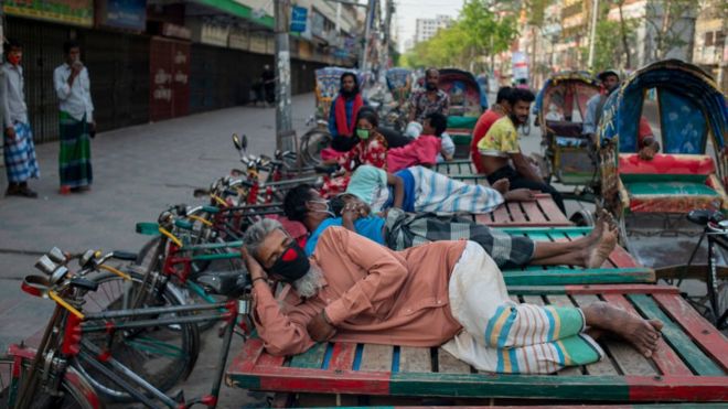 Поденщики, которые являются трехколесными транспортными средствами, спят в своих фургонах, поскольку работы не ведутся из-за частичной блокировки для защиты людей от распространения коронавируса (COVID-19) в Нараянгандже, Бангладеш.