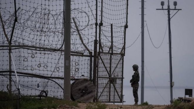9 мая 2017 года военнослужащий стоит на страже у входа в ограду Демилитаризованной зоны (ДМЗ) на крошечном отдаленном острове Гёдонг, расположенном к западу от Сеула. Укрепленная граница почти непроницаема