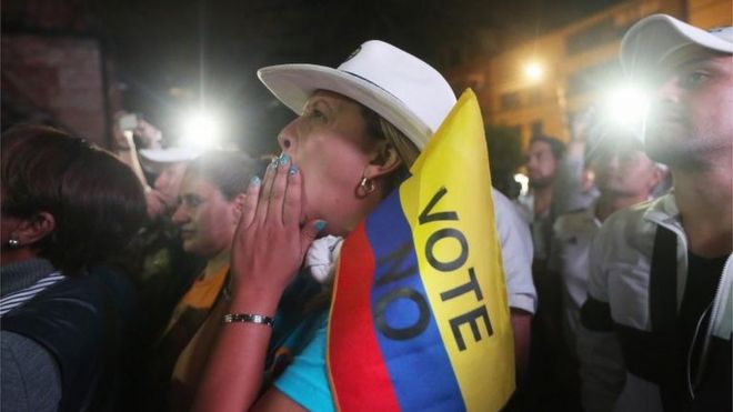 Una mujer sostiene una bandera que dice "voté no".