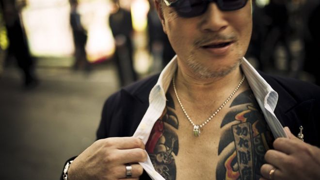 Мужчина демонстрирует татуировки