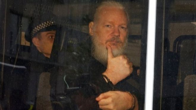 Assange gestures with a thumbs up after he was arrested by Met Police officers at Ecuador's embassy in London