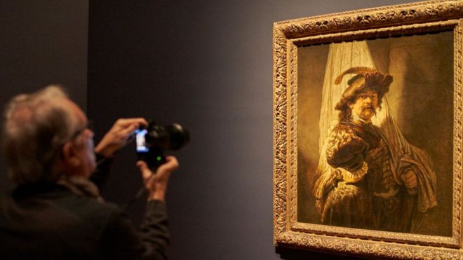 Un hombre retrata la pieza de Rembrandt, El Abanderado, en un museo