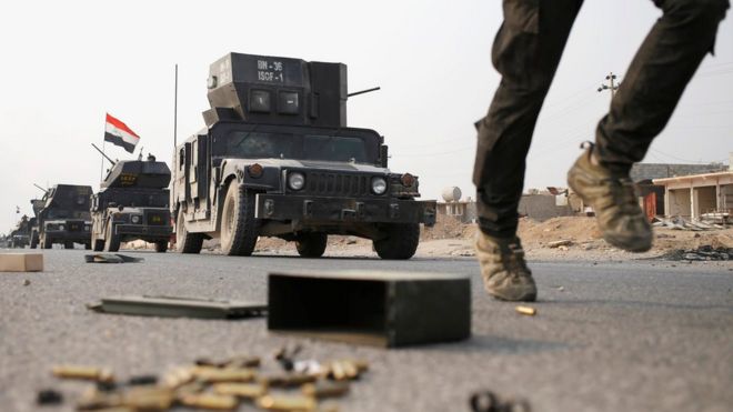 Военнослужащий иракского спецназа бежит в качестве броневика на дороге возле Мосула, Ирак (25 октября 2016 года)