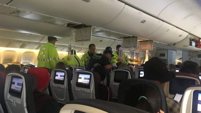 Emergency workers assist passengers of Air Canada AC 33 flight, which diverted to Hawaii after turbulence