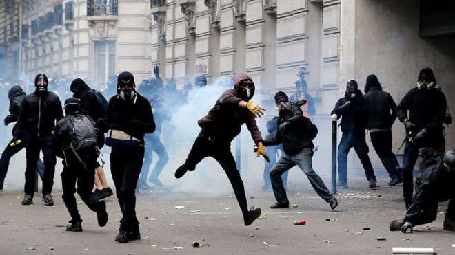 Протестующий отбрасывает канистру со слезоточивым газом во время столкновений с полицией по охране общественного порядка во время национальной демонстрации и забастовки против реформы трудового законодательства в Париже, Франция, 14 июня 2016 года