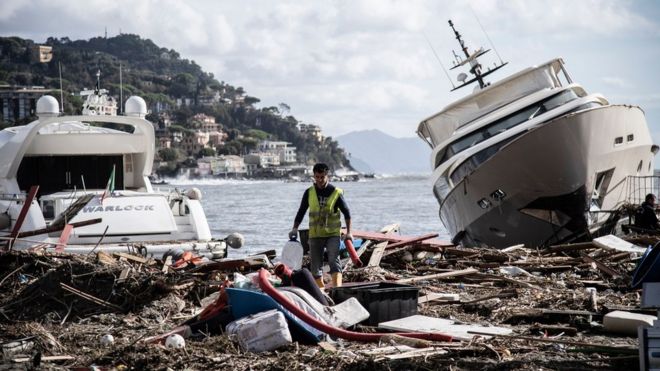 Человек идет по мусору между двумя яхтами после того, как шторм обрушился на гавань и разрушил часть плотины прошлой ночью 30 октября 2018 года