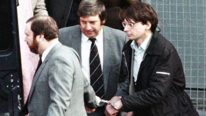 Настоящего Денниса Нильсена (справа) ведет полиция в наручниках в 1983 году