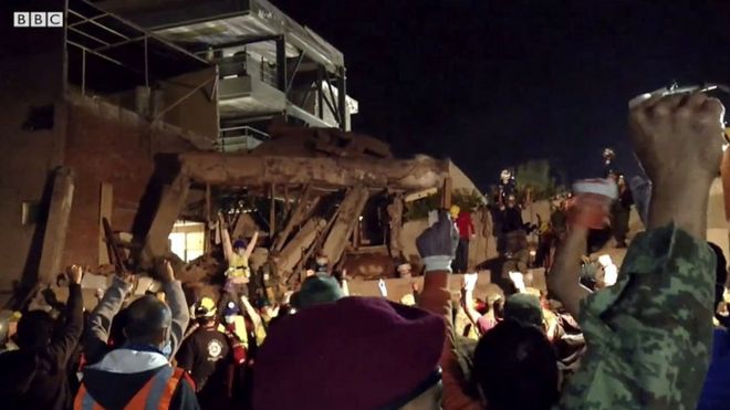 Спасатели и волонтеры, работающие после землетрясения на завалах в Мексике, поднимают вверх кулаки, чтобы создать тишину.