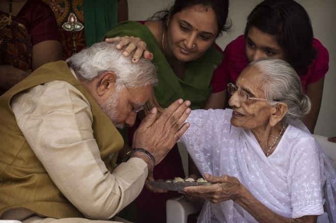 Лидер BJP Нарендра Моди (слева) благословлен своей матерью Хирабен Моди на крыльце после того, как 16 мая 2014 года в Ахмедабаде, Индия, попросил ее благословения.
