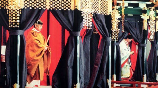 Император Акихито (слева) в традиционном японском костюме стоит внутри Такамикура (Императорский трон) во время церемонии возведения на престол в Императорском дворце - справа от императрицы Мичико - 12 ноября 1990 года