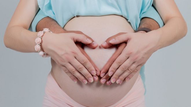 Беременная женщина с руками вокруг ее шишка