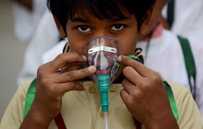 Индийский школьник корректирует маску перед началом мероприятия, чтобы рассказать о проблеме загрязнения воздуха в Нью-Дели 4 июня 2015 года, в канун Всемирного дня окружающей среды.