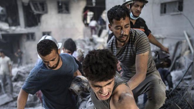 Hombres rescatando a heridos tras uno de los ataques de Israel.