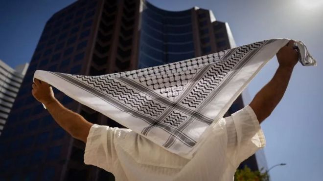 شخص يرفع الكوفية الفلسطينية.