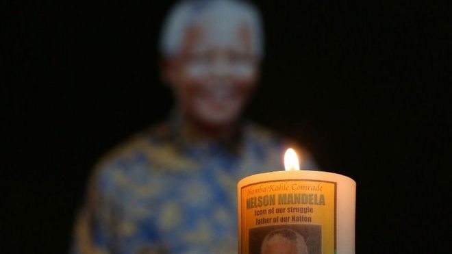 Candle lit in front of image of Nelson Mandela