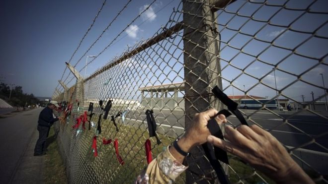 Protesters against the relocation of US Marine Corps Air Station Futenma ties black and red ribbons on the fence of Camp Schwab, an American base near a planned relocation site, in Nago, Okinawa Prefecture Monday, 23 March 2015