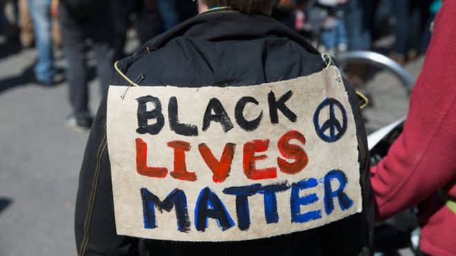 A protestor wearing a sign saying "Black Lives Matter"