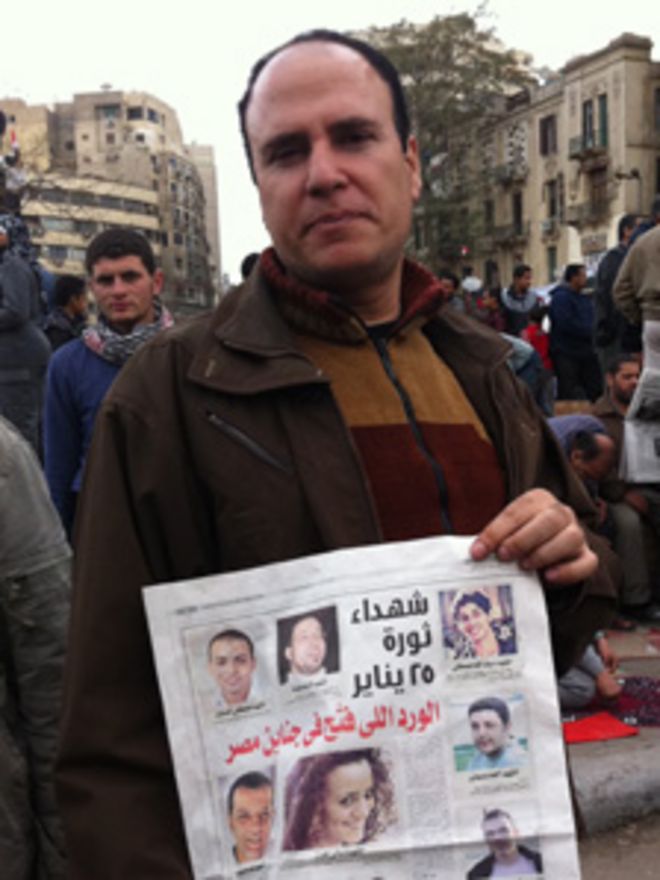Протестующие держат в газете репортаж о погибших демонстрантах