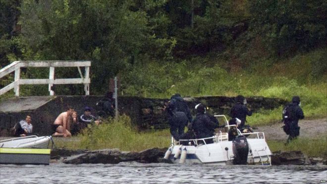 Вооруженные полицейские нацеливают свое оружие, в то время как люди укрываются после стрельбы на острове Утоя, примерно в 40 км к юго-западу от Осло, 22 июля 2011 г.