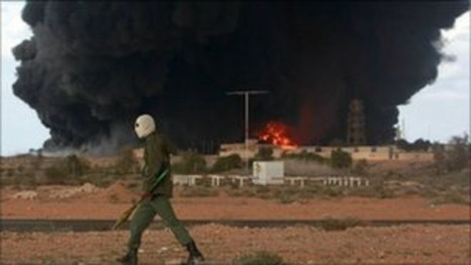 Мятежник проходит мимо горящего нефтяного терминала