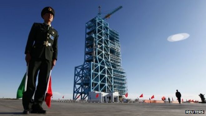 Китайский солдат стоит рядом с ракетой Long March II-F, загруженной беспилотным космическим модулем Китая Tiangong-1, на стартовой площадке в центре запуска спутников Jiuquan, провинция Ганьсу, в среду