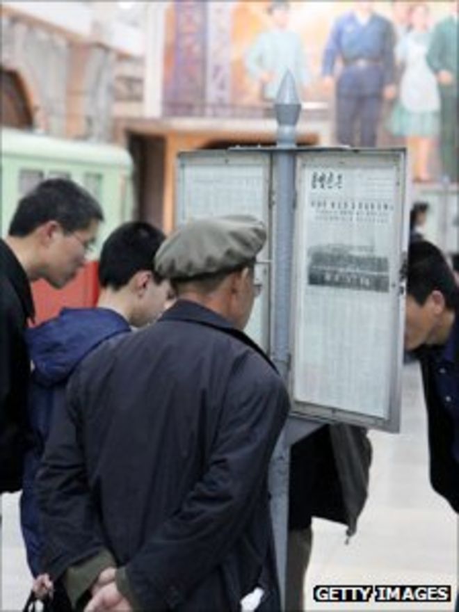 Северокорейцы читают газету у станции метро