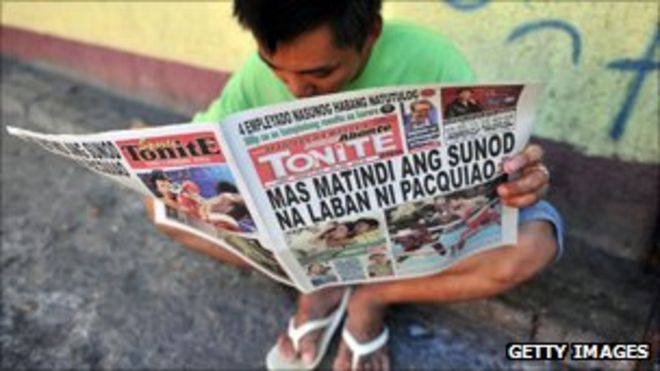 Человек читает газету на улице Манилы