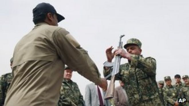 Бывший частный охранник (слева) передает свое оружие Джамалу Абдулу Насеру Сидики, главе Афганских сил общественной защиты