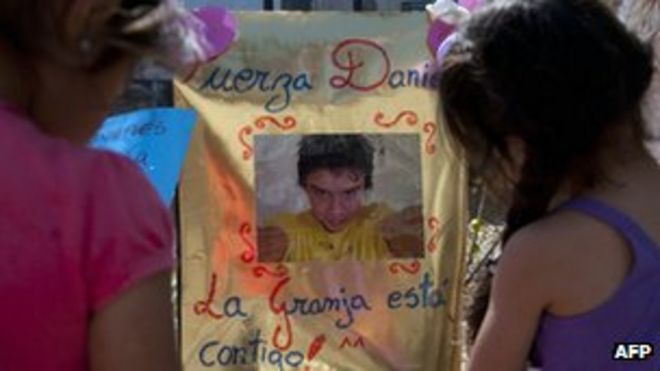 Две девушки смотрят на фотографию чилийца Даниэля Самудио, размещенную за пределами государственной больницы в Сантьяго 28 марта 2012 г.